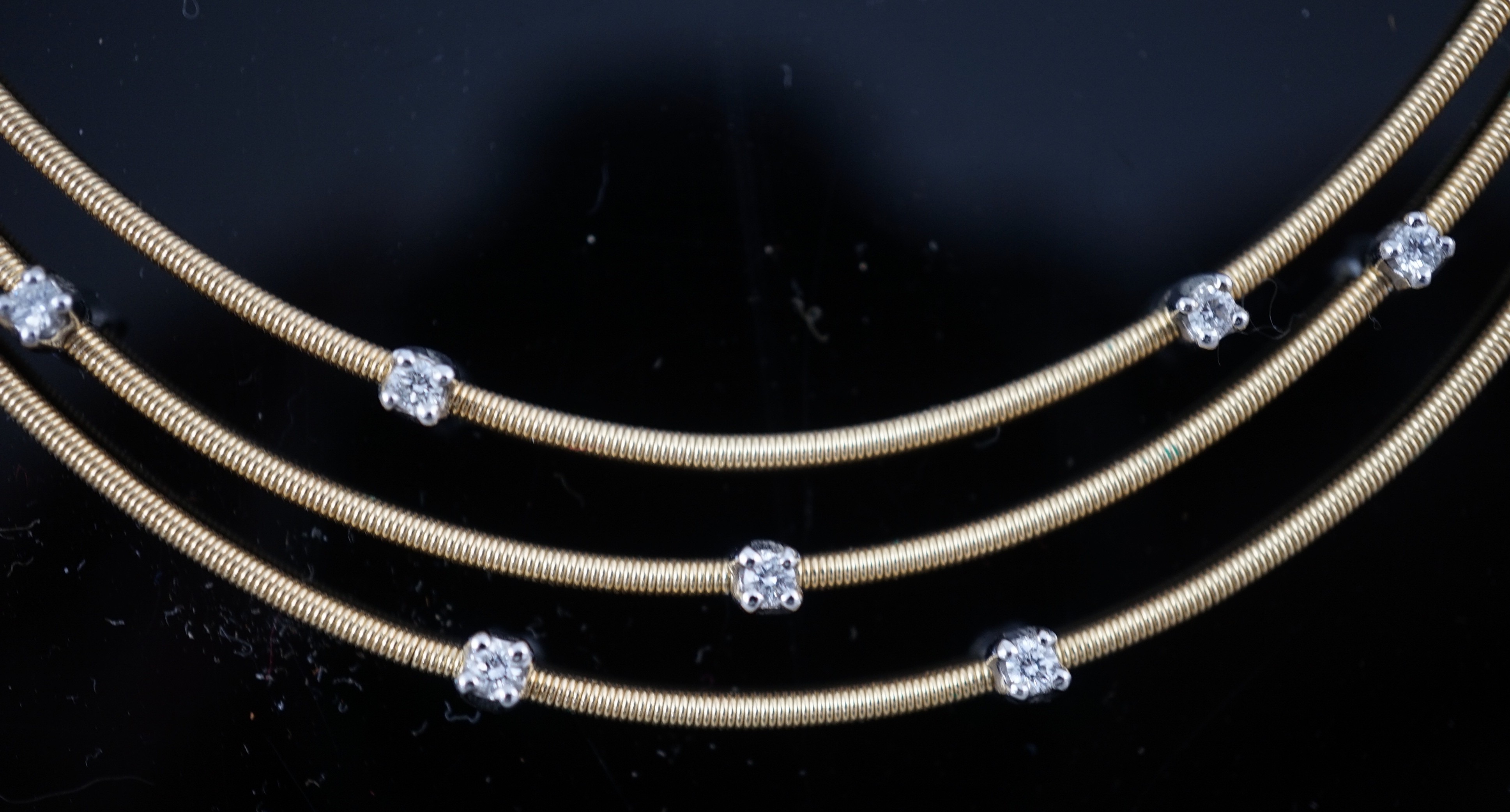 A modern Italian Marco Bicego 18ct gold and eleven stone diamond chip set triple strand necklace